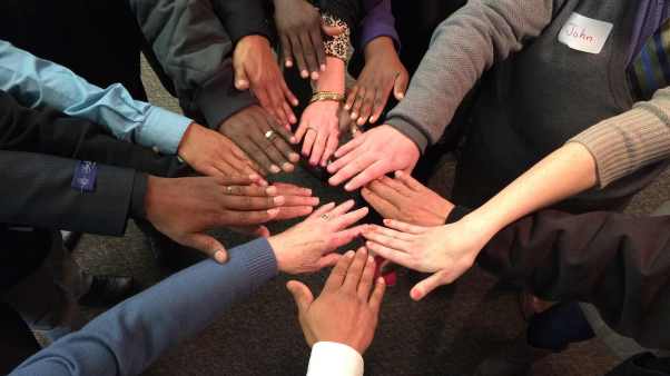 The members of Zion Lutheran Church's "oikos" committee, which works across four people groups to organize the church and its ministries, place their hands together in a sign of solidarity.