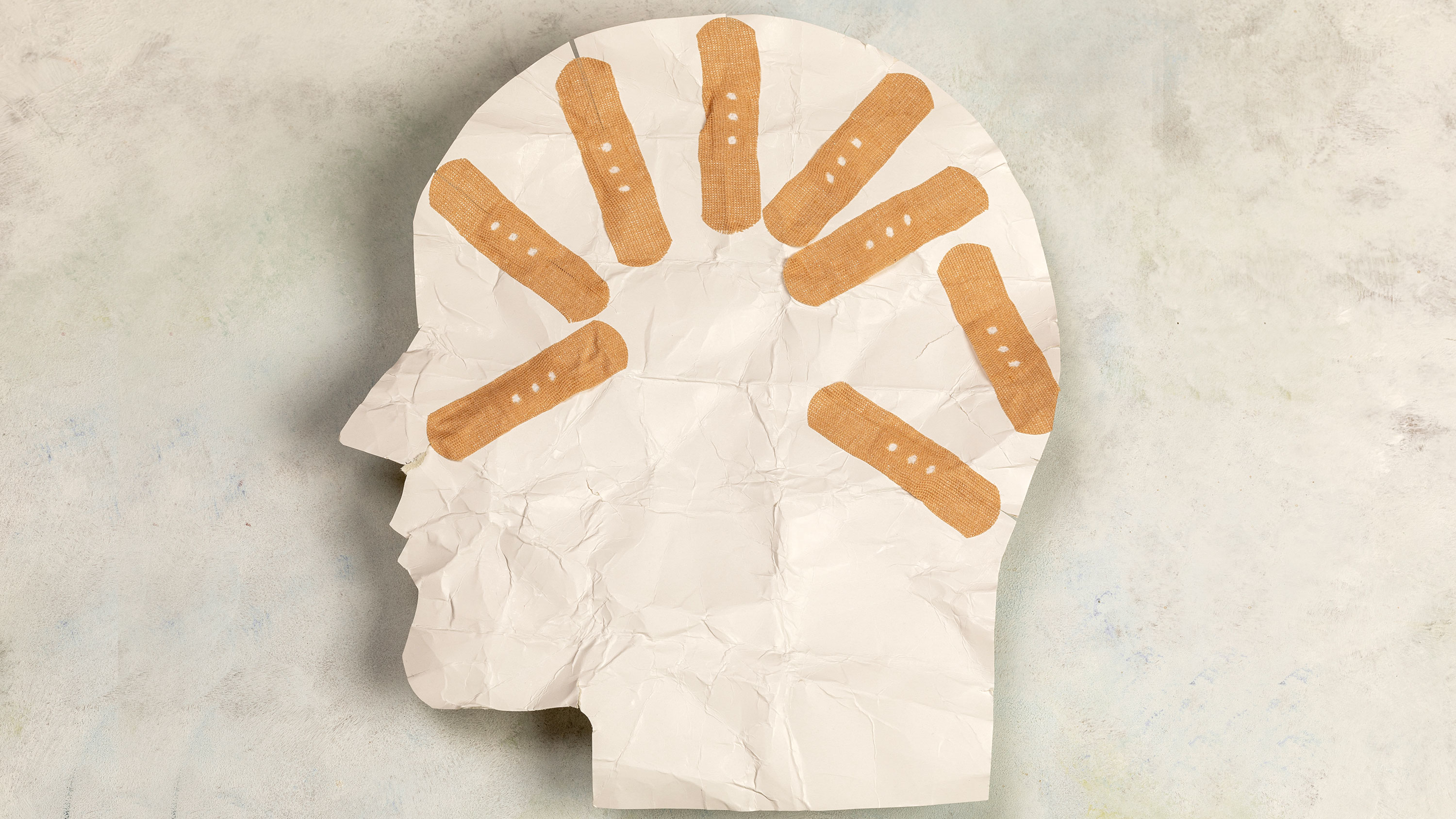 paper art of a head's profile with bandaids.