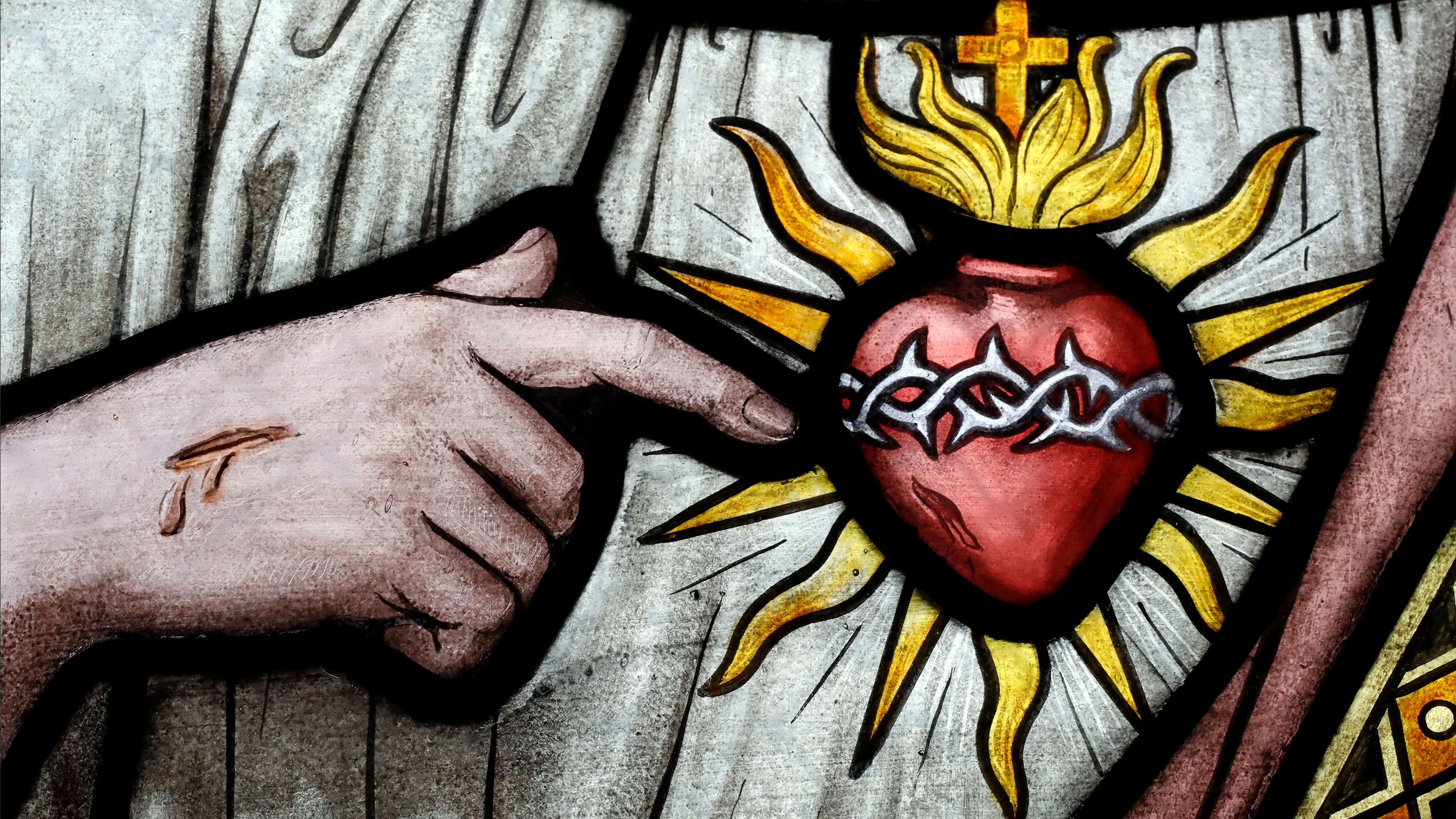 Close up of a stained glass window. Jesus pointing to sacred heart.