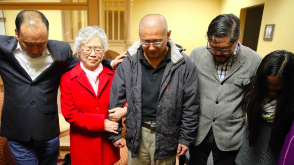 Kenneth Bae prays with his family and pastor Eugene Cho.