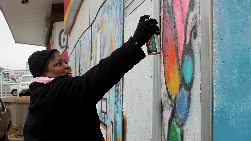 Adrienne Hawkins participating in Paint for Peace, a project aimed at spreading colorful messages of hope in Ferguson.