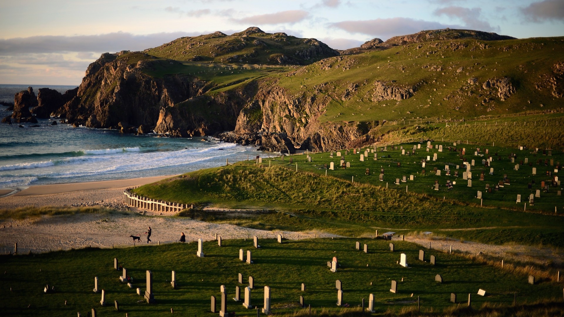 A couple walk their dogs on Dail Mor beach in Lewis, Scotland.