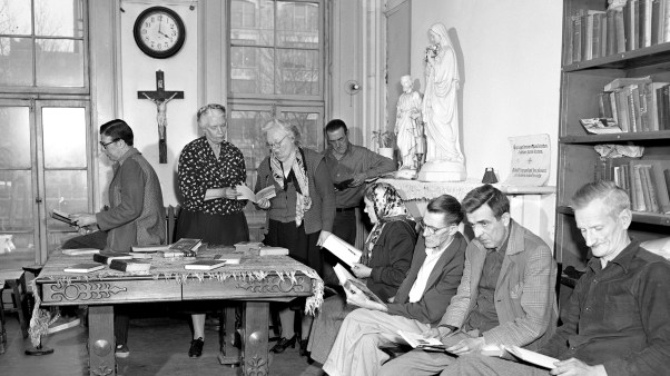 Dorothy Day (in dotted dress) looks at book in House of Hospitality library.