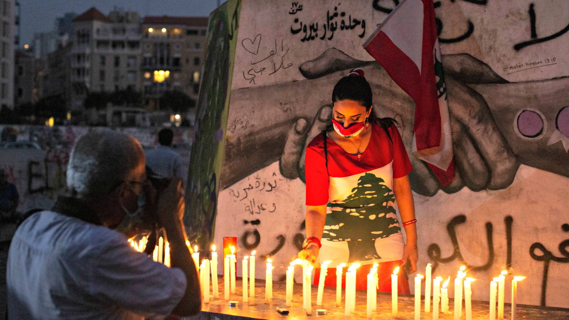 A woman wearing a Lebanese flag-themed dress participates in a Beirut vigil to mark one month since the huge explosion in the capital’s port.