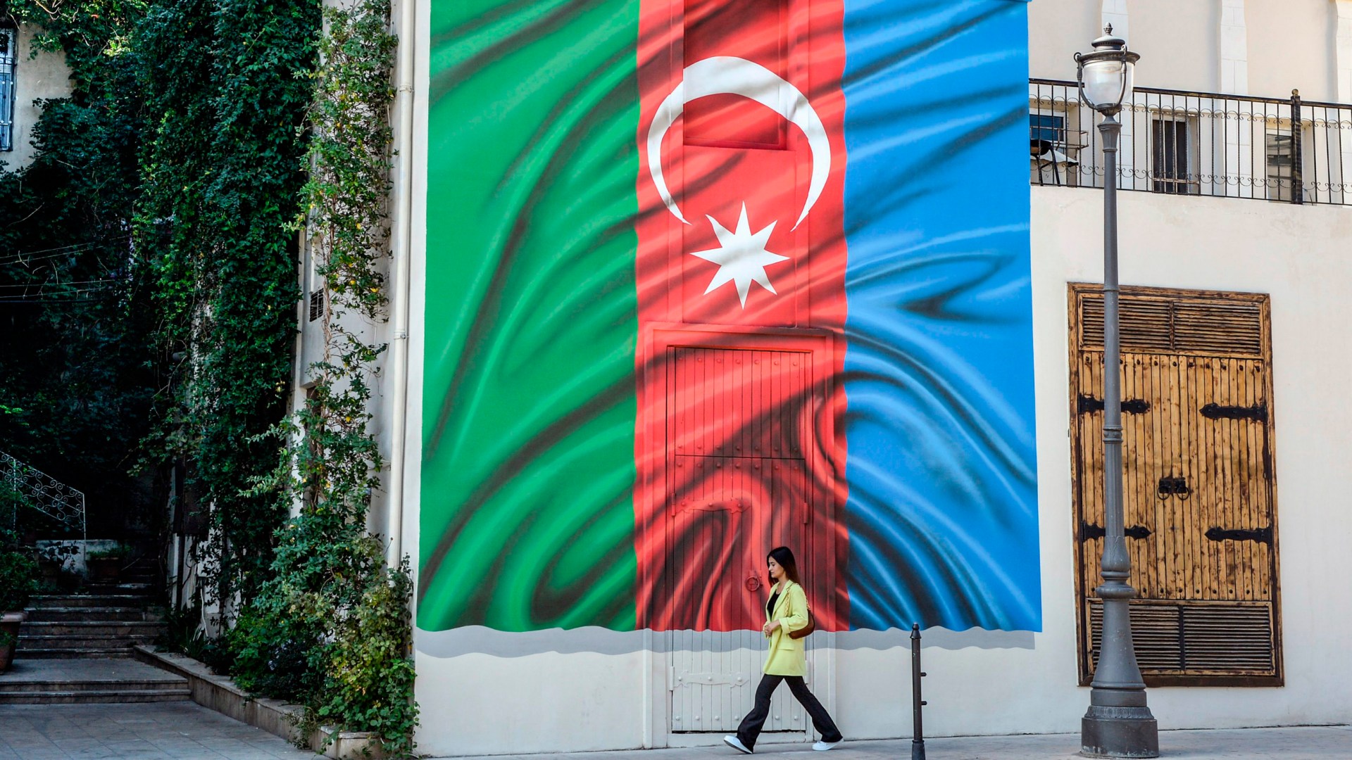 A woman walks past a building with a painting of the Azerbaijani flag on its wall in Baku on October 14, 2020, amid the ongoing military conflict between Armenia and Azerbaijan over the breakaway Nagorno-Karabakh region.