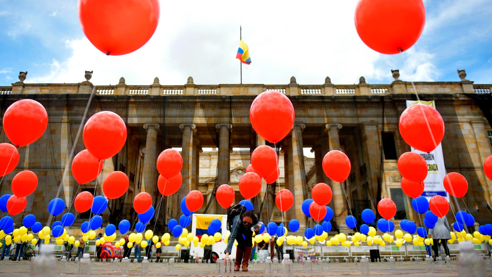 A woman places balloons with the colors of the Colombian national flag at Bolivar Square in Bogota on October 2 during a symbolic act commemorating the fourth anniversary of the referendum held to ratify a historic peace accord between the Colombian government and the FARC guerrillas, which voters narrowly rejected.