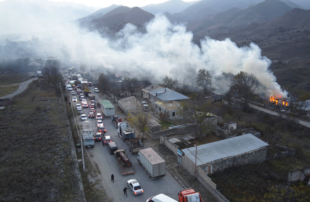 Smoke rises from a burning house as cars and trucks stuck in a huge traffic jam climbing along the road from Kelbajar leaving the separatist region of Nagorno-Karabakh to Armenia on Nov. 14.