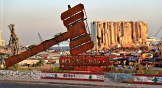A justice symbol monument is seen August 4, 2021, in front of towering grain silos that were gutted in the massive August 2020 explosion at the port of Beirut that claimed the lives of more than 200 people in Lebanon.