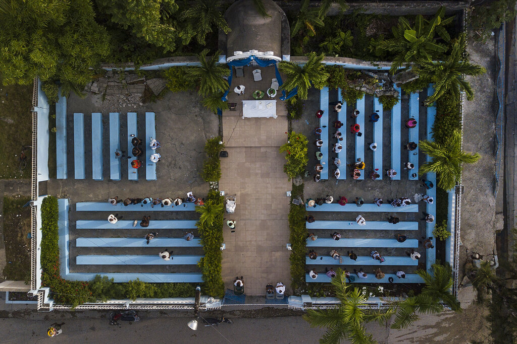 Parishioners attend a mass on the grounds next to an earthquake-damaged cathedral in Les Cayes, Haiti, on Sunday, August 22, 2021, eight days after a 7.2 magnitude earthquake hit the area.