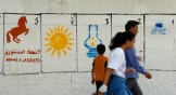 A Moroccan family walk past electoral paintings representing political party logos for the Sept. 8 municipal elections in Casablanca.