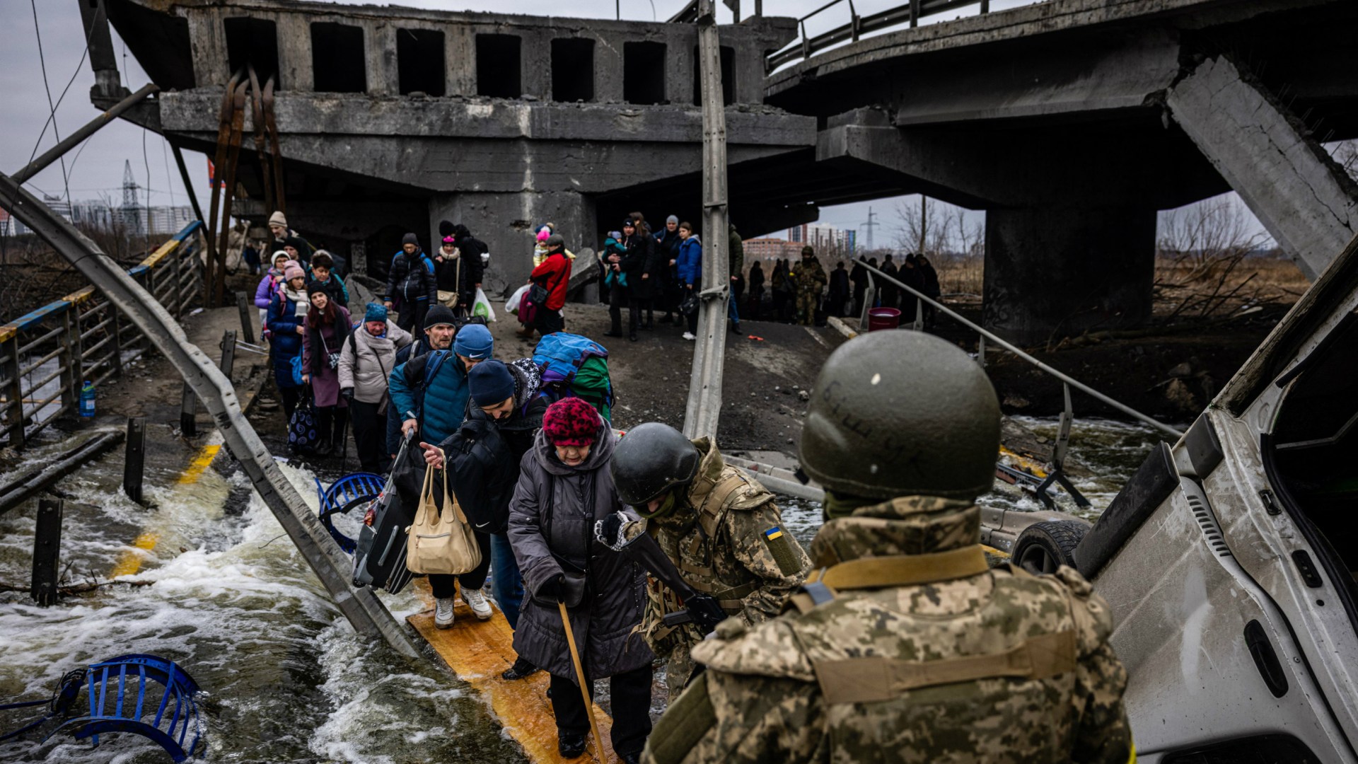 Evacuees cross a destroyed bridge as they flee the city of Irpin, northwest of Kyiv, on March 7, 2022.