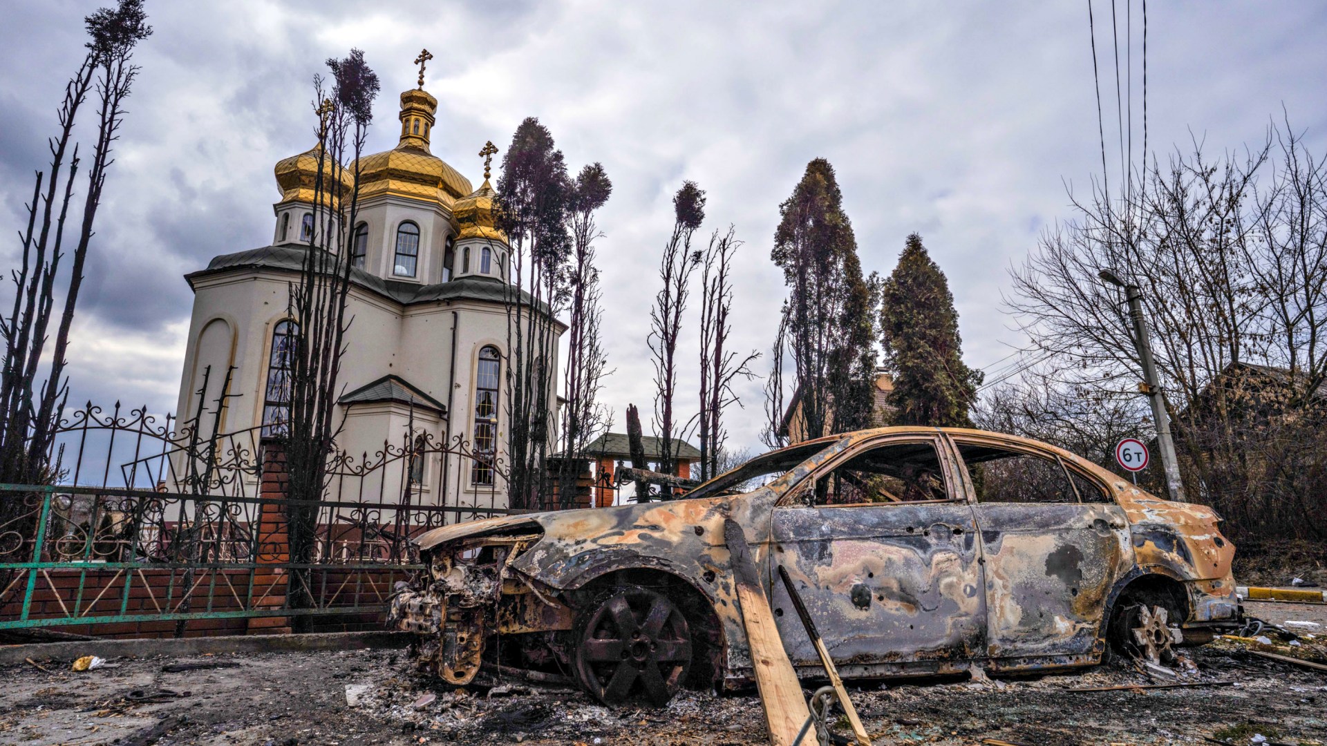 A damaged church and burnt car in Irpin, Ukraine, caused by a Russian military attack on March 9, 2022.