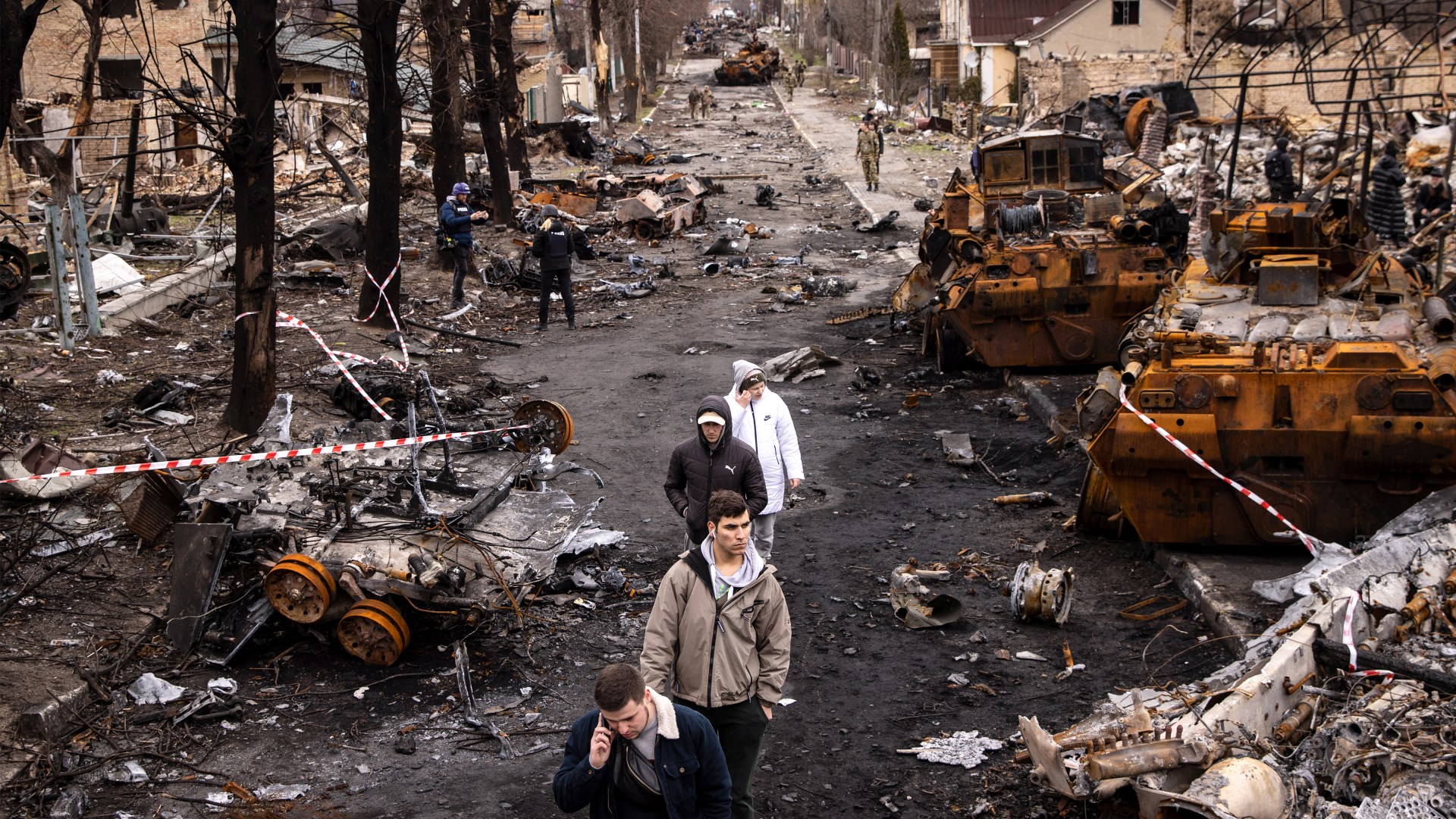 People walk through debris and destroyed Russian military vehicles on a street in Bucha, Ukraine, on April 6, 2022.