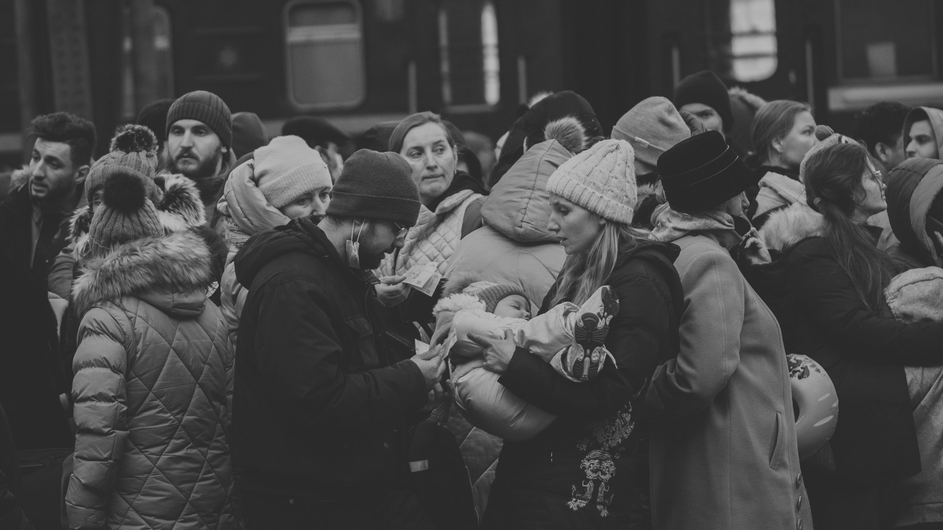 A woman, man, and their child stand on a crowded train station platform in Lviv, Ukraine, in February 2022.