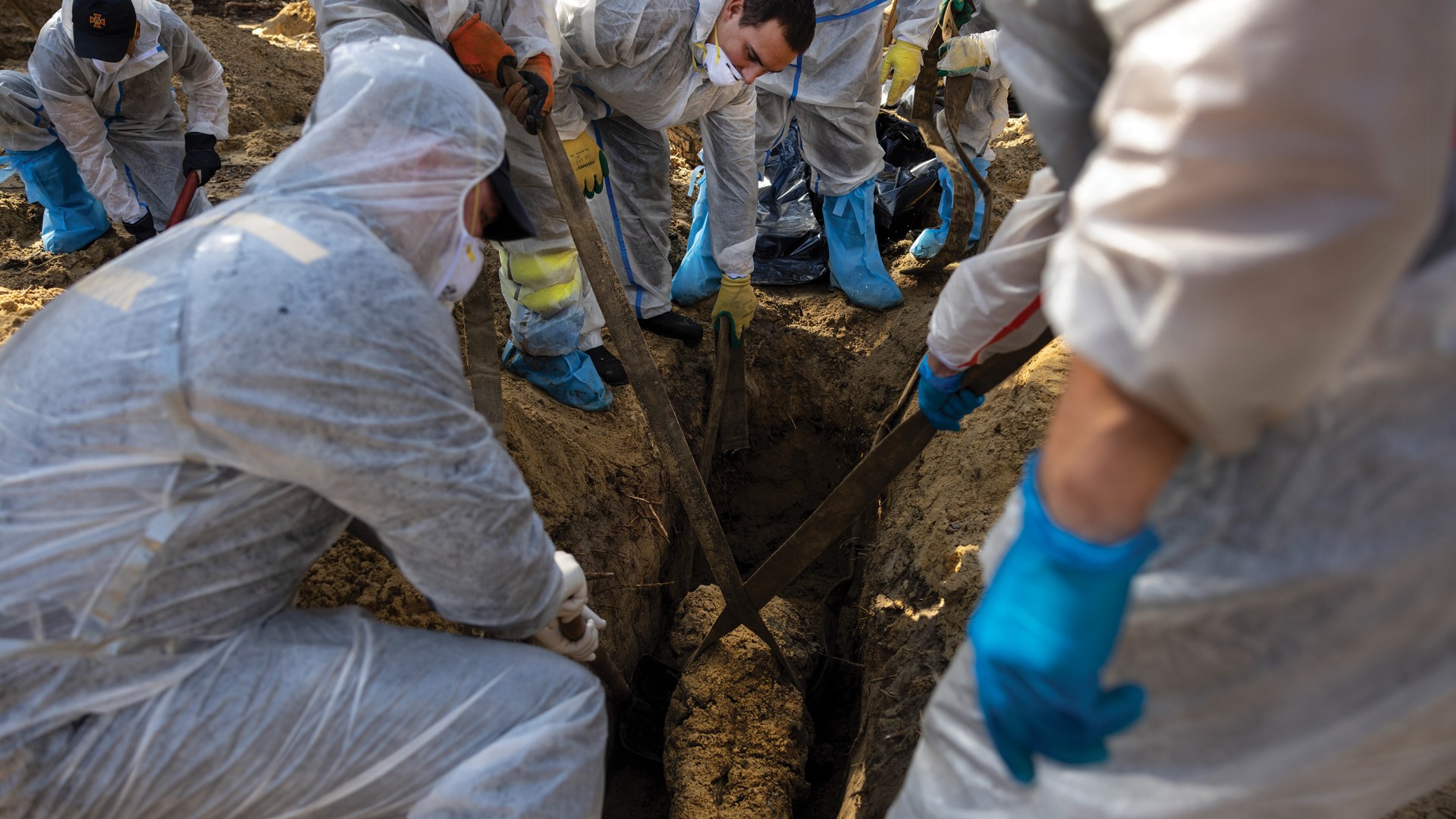 Rescue workers and forensic police exhume bodies from unidentified graves in Izium, Ukraine