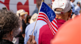 A woman in Georgia waves a flag that says “pray” at a rally for US Senate candidate Herschel Walker.