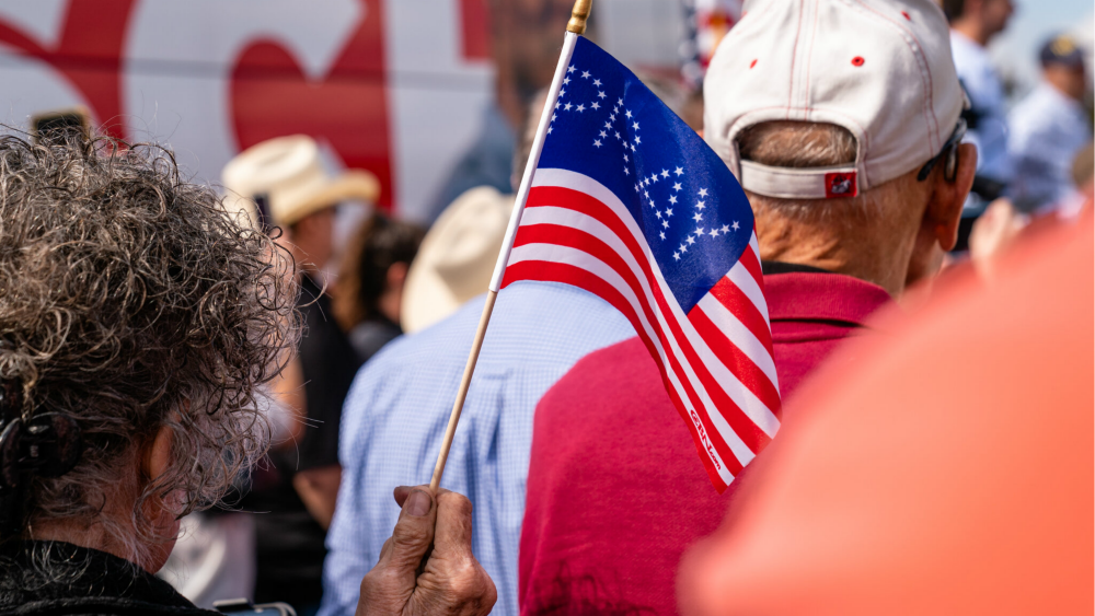 A woman in Georgia waves a flag that says “pray” at a rally for US Senate candidate Herschel Walker.