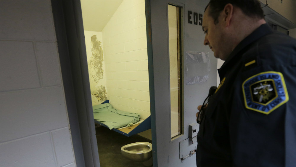 A prison guard looks into an isolation cell.