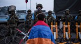 A protester wearing the Armenian national flag stands in front of Russian peacekeepers blocking the road outside Stepanakert, capital of Nagorno-Karabakh, on December 24, 2022.