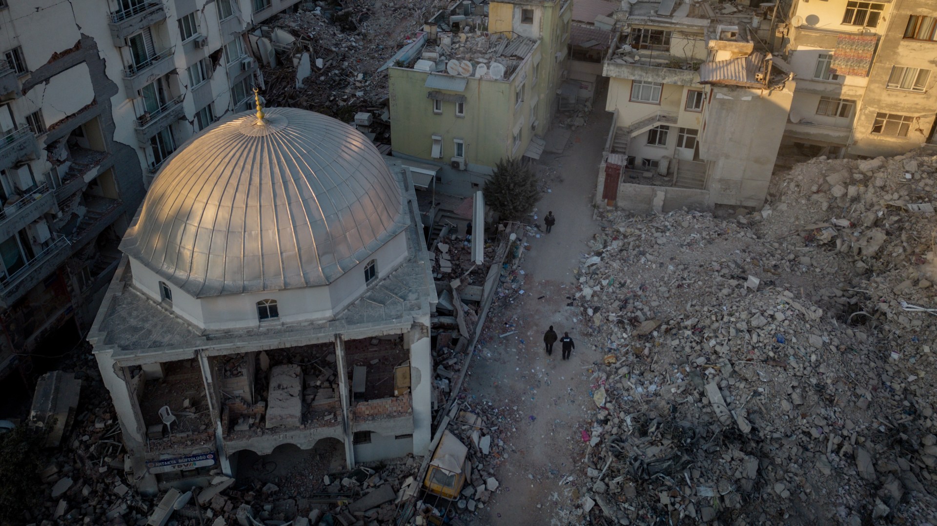 People walk past a destroyed mosque in Hatay, Turkey on February 20, 2023 after earthquakes caused widespread destruction in southern Turkey and northern Syria and killed more than 40,000 people.