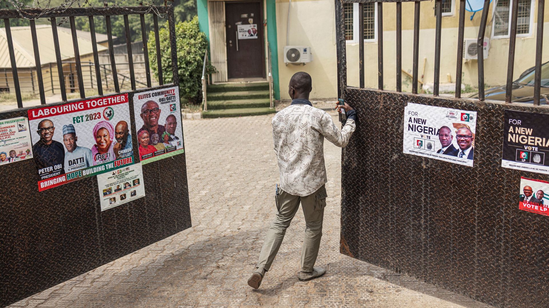 A man opens the gate of Labour Party candidate Peter Obi offices in Abuja on February 23, 2023, ahead of the Nigerian presidential election scheduled for February 25, 2023.