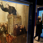 A woman walks past The painting "Luther Preaching from the Pulpit" by Alexandre Struys on exhibition in Eisenach to celebrate the 500th anniversary of Luther's translation of the Bible.