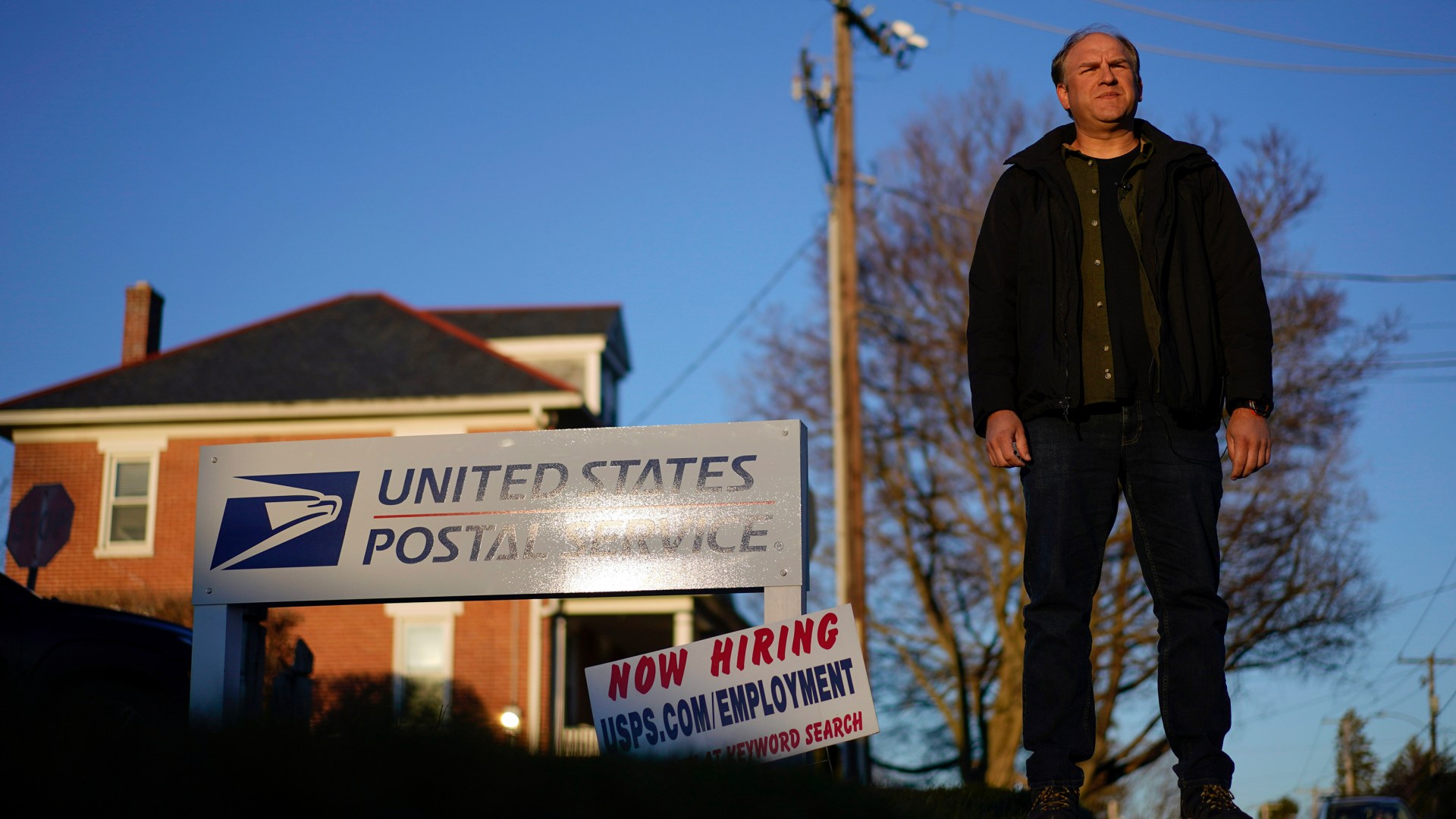 Gerald Groff, a former postal worker whose case will be argued before the Supreme Court, stands during a television interview near a "Now Hiring" sign posted at the roadside at the United State Postal Service.