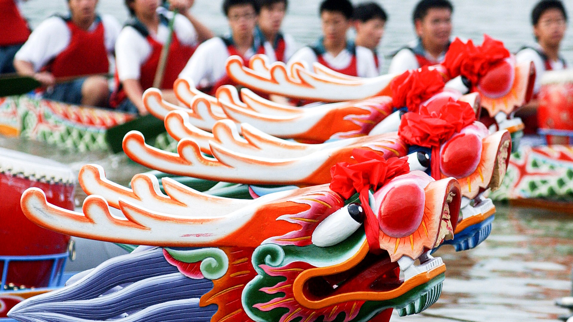 A team participating in the international Dragon Boat Festival rows past several empty dragon boats.