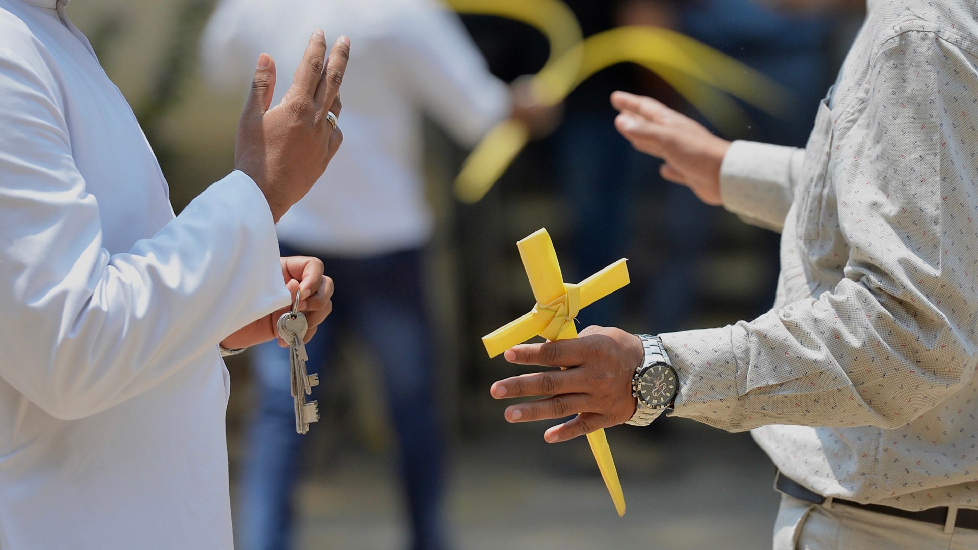 A Christian devotee holds a holy cross made out of palm leaf as he speaks with a pastor in India.