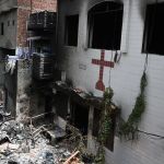 Men stand amid debris outside the torched Saint John Church in Jaranwala on the outskirts of Faisalabad on August 17, 2023, a day after an attack by Muslim men following spread allegations that Christians had desecrated the Quran.