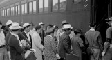 Evacuees of Japanese ancestry in Woodland, California, board a train for Merced Assembly center.