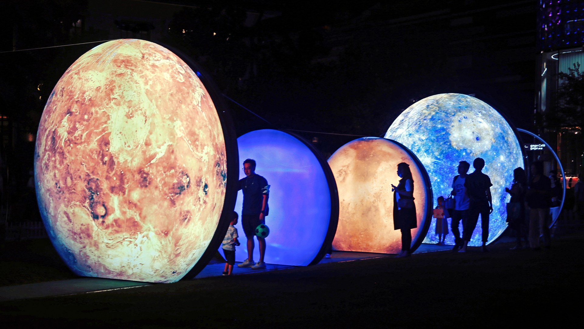 People look at illuminated art installations of the moon and the earth on display for the Mid-Autumn Festival.