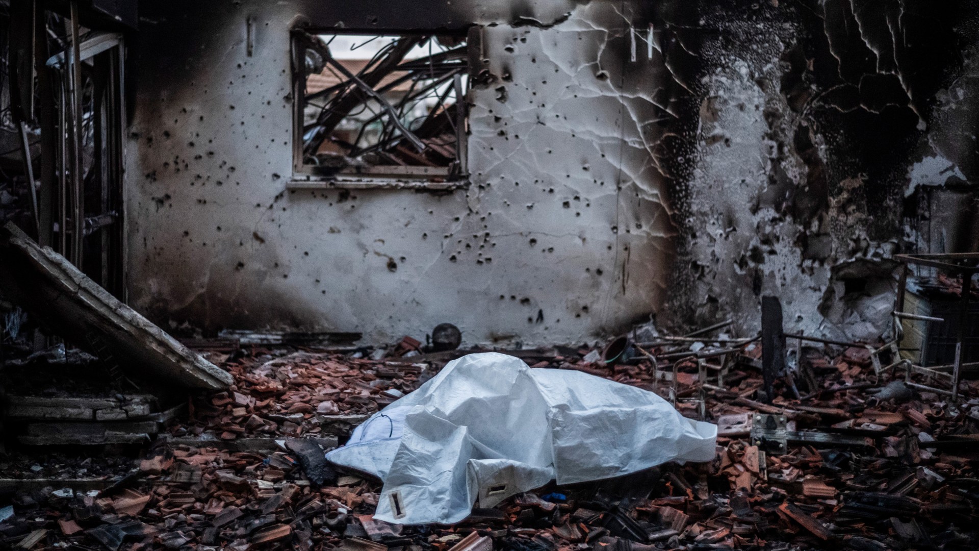 A body lies covered in a house destroyed as a result of the Israel-Hamas war.