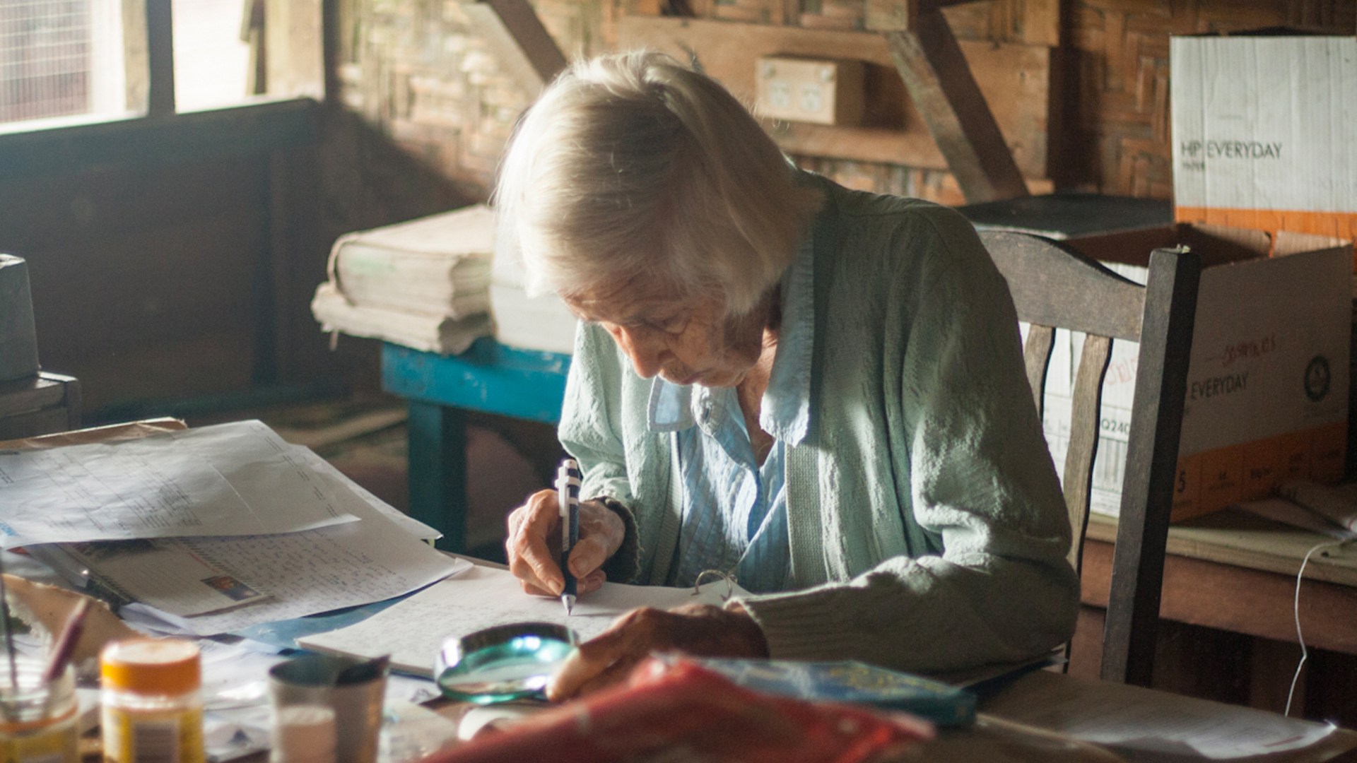 Lin Calvert using her magnifying glass to read papers.