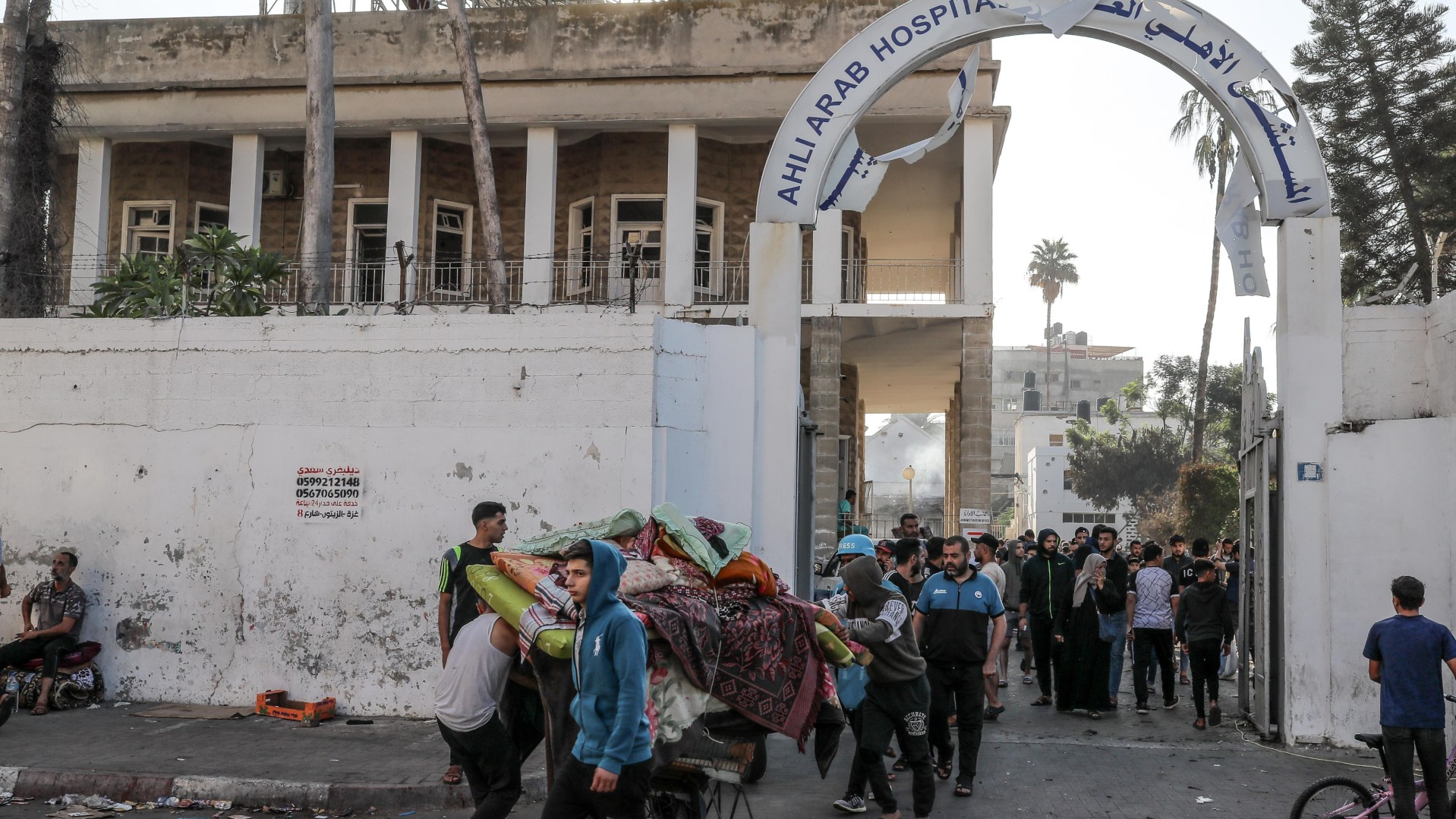 Palestinians carry usable items from the heavily damaged Al-Ahli Baptist Hospital building after bombing in Gaza City, Gaza, on October 18, 2023.