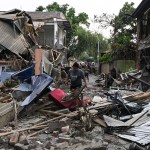 A woman walks through the wreckage of a building that was set on fire and vandalised by mobs in Khumujamba village.