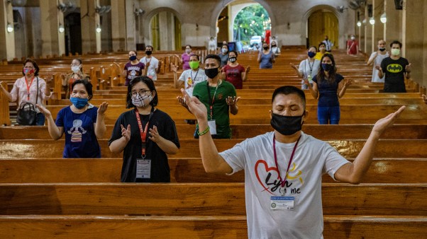 Worshippers wearing face masks stand far apart from one another to practice social distancing as they take part in Sunday service.