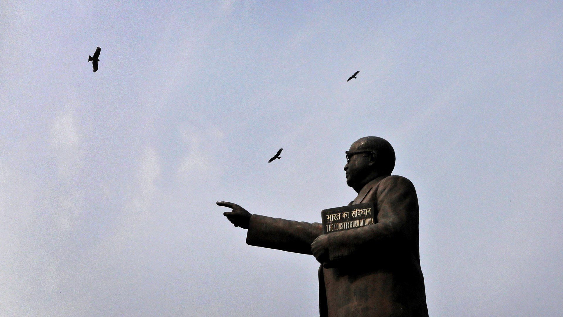 Birds fly over a statue of B.R. Ambedkar, who is regarded as the architect of India's constitution.