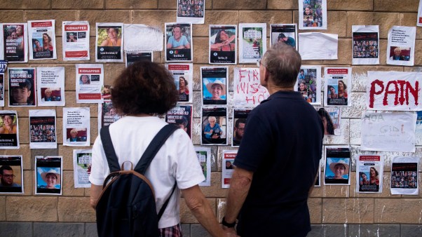 People look at a wall with photos of hostages kidnapped in the Hamas attack.
