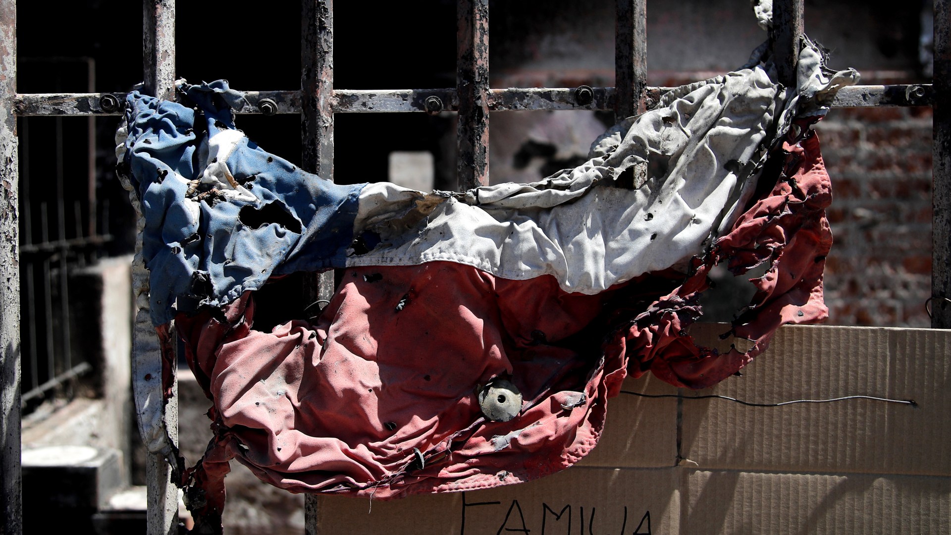 A burned Chilean flag is seen outside a burned house after a forest fire.