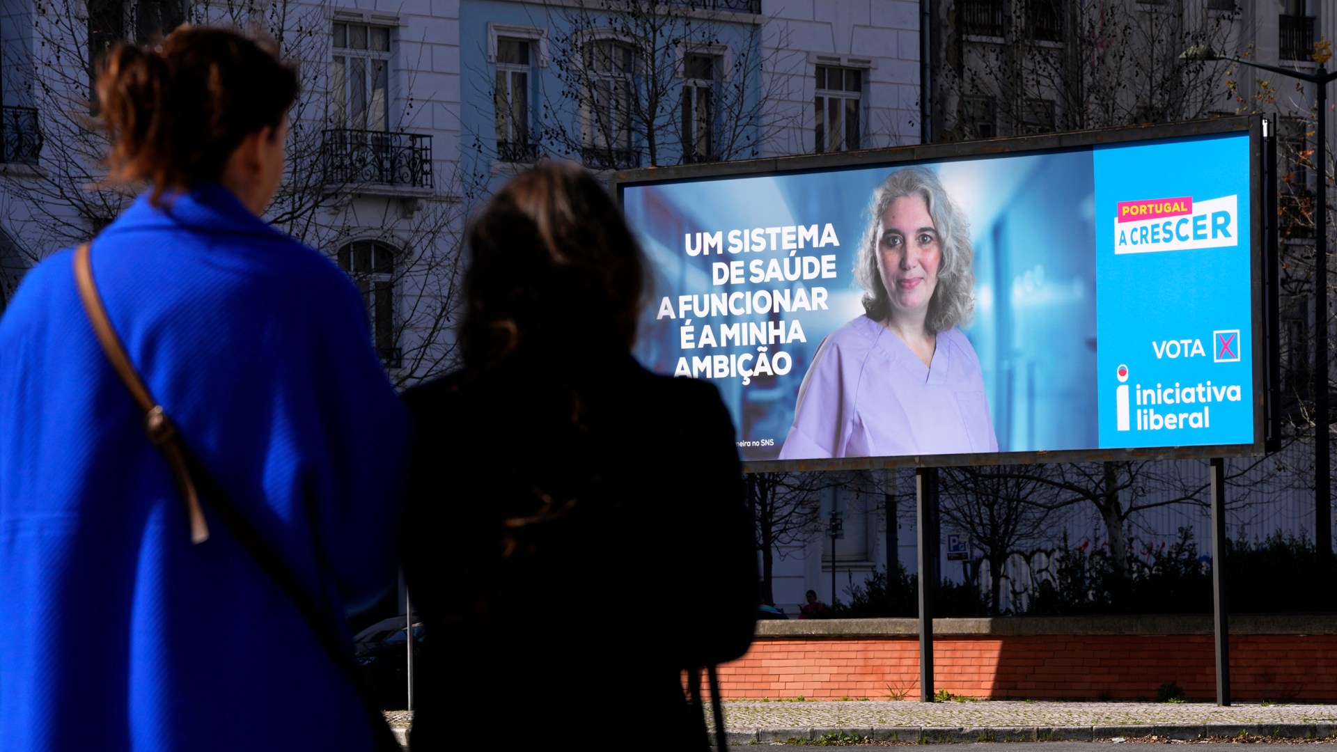 People walk by an election campaign billboard in Lisbon.
