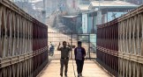 An Indian police officer and an Indian man walk on a bridge across Tiau river along the India-Myanmar border in Mizoram.