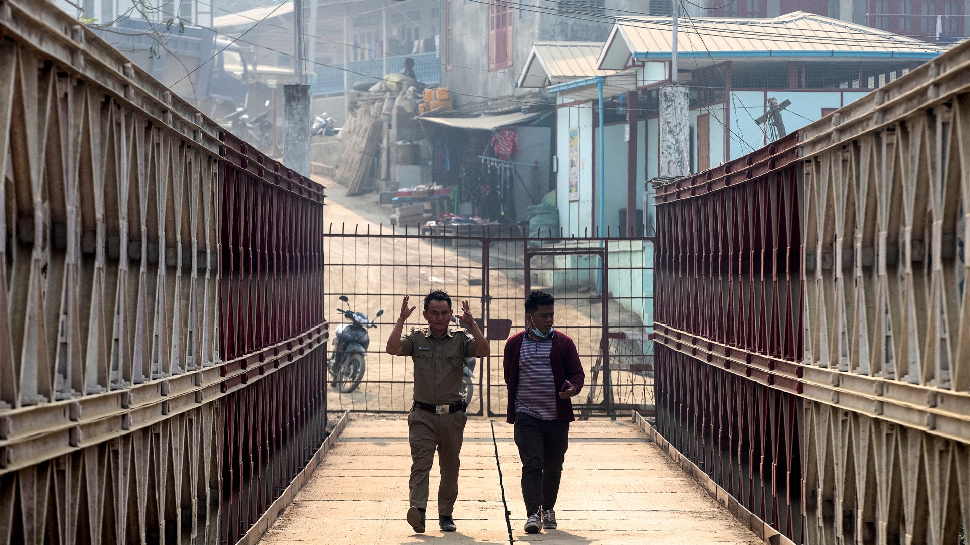 An Indian police officer and an Indian man walk on a bridge across Tiau river along the India-Myanmar border in Mizoram.