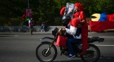 Government supporter rides on the back of a motorbike holding an image of Venezuelan President Nicolas Maduro.