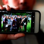 Amos Cao holds a family photo showing his father, Pastor John Cao (far right).