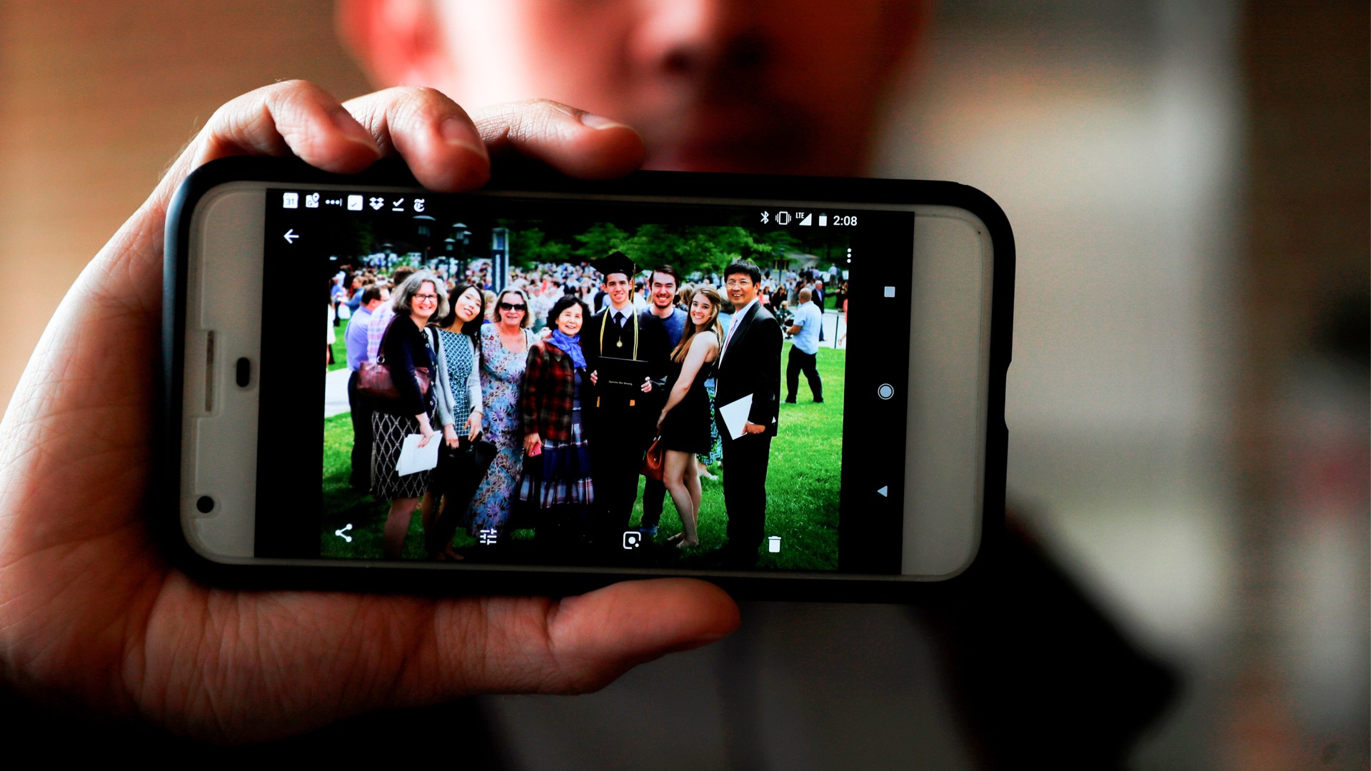 Amos Cao holds a family photo showing his father, Pastor John Cao (far right).