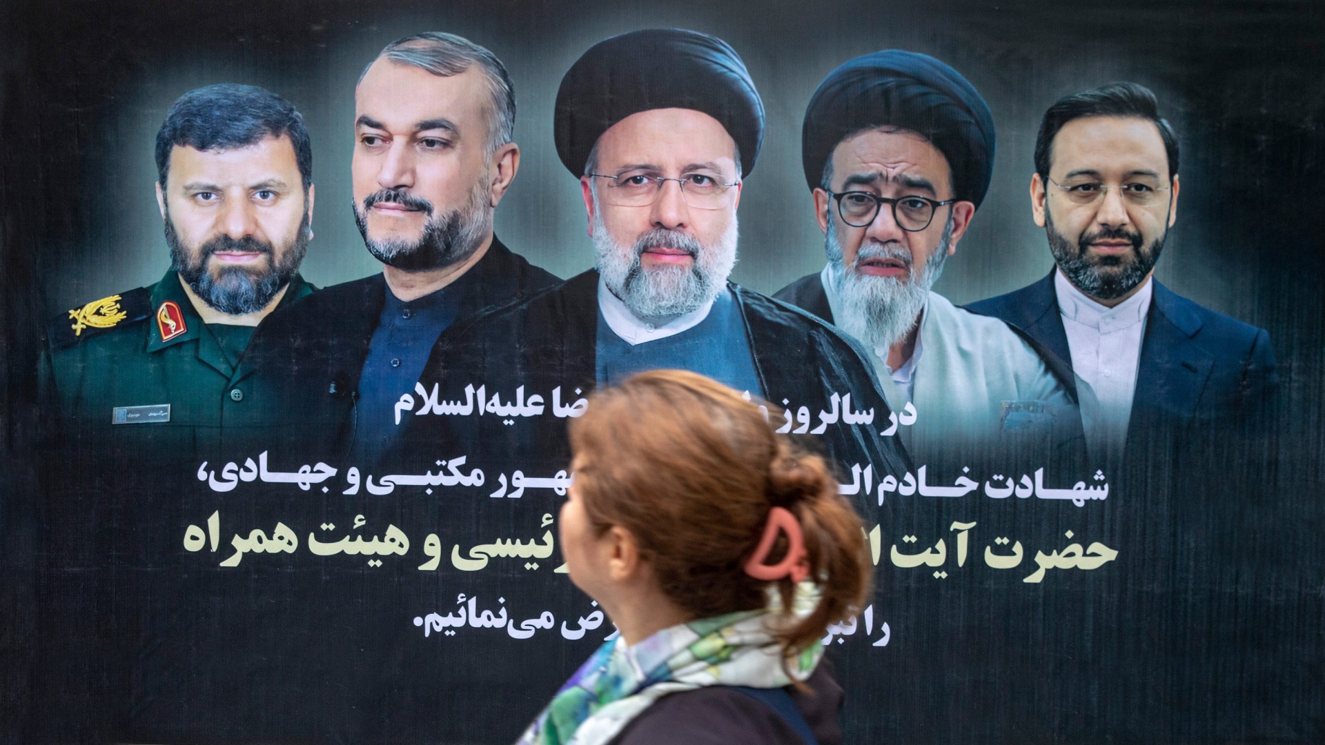 A woman passes by a poster of Iran's late president Ebrahim Raisi who died in a helicopter crash.