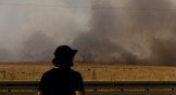 A man looks as smoke rises over the Golan Heights after a Hezbollah rocket attack on Northern Israel.