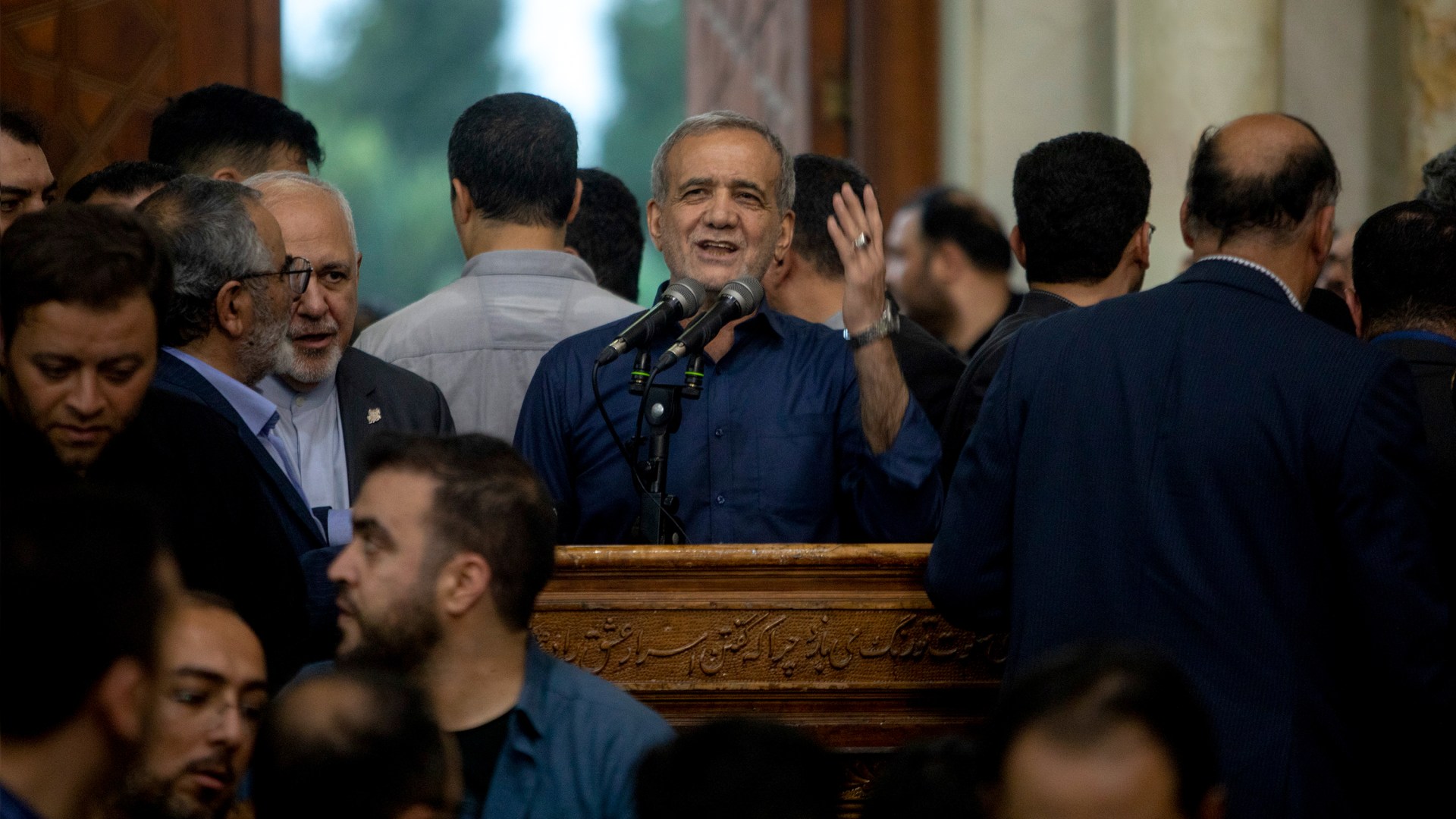 Newly-elected Iranian President Masoud Pezeshkian (center) speaks during a visit to a shrine.