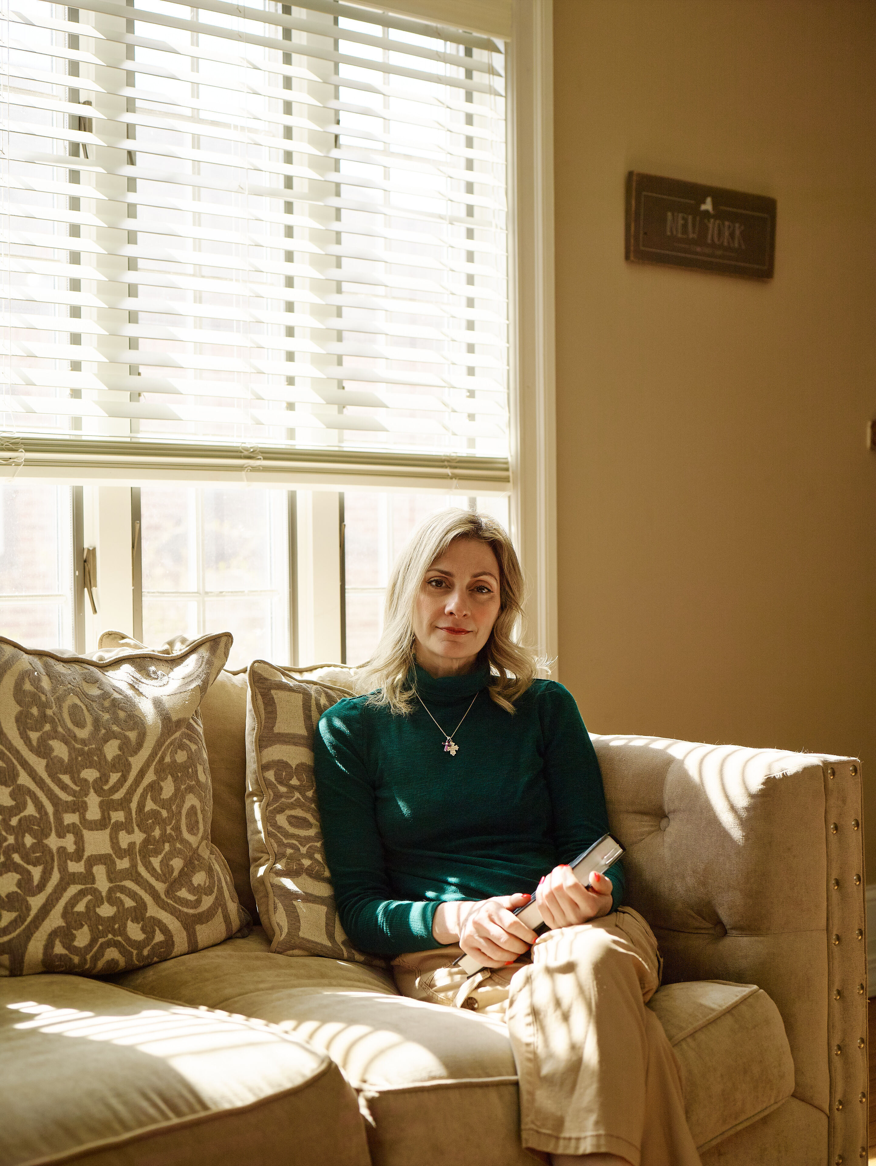 A photo of Jennifer Nizza on a couch with a book in her hand
